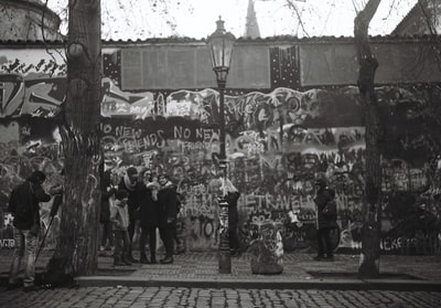 白天，人们站在白色和棕色的水泥建筑物前